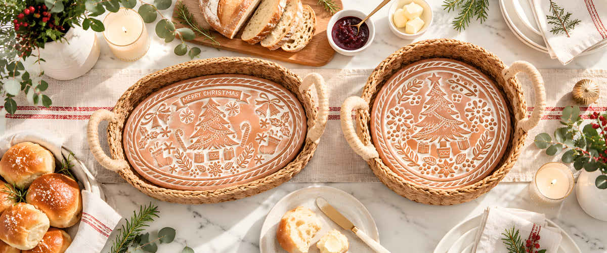 Oval and round terracotta Christmas bread warmers in seagrass baskets on a holiday table