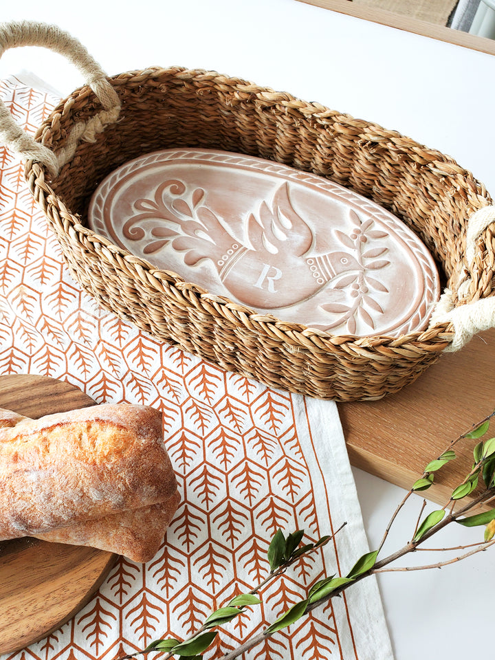 Hand engraved terracotta plate with a bird & leaf design into an oval basket and hand screen-printed tea towel on natural cotton