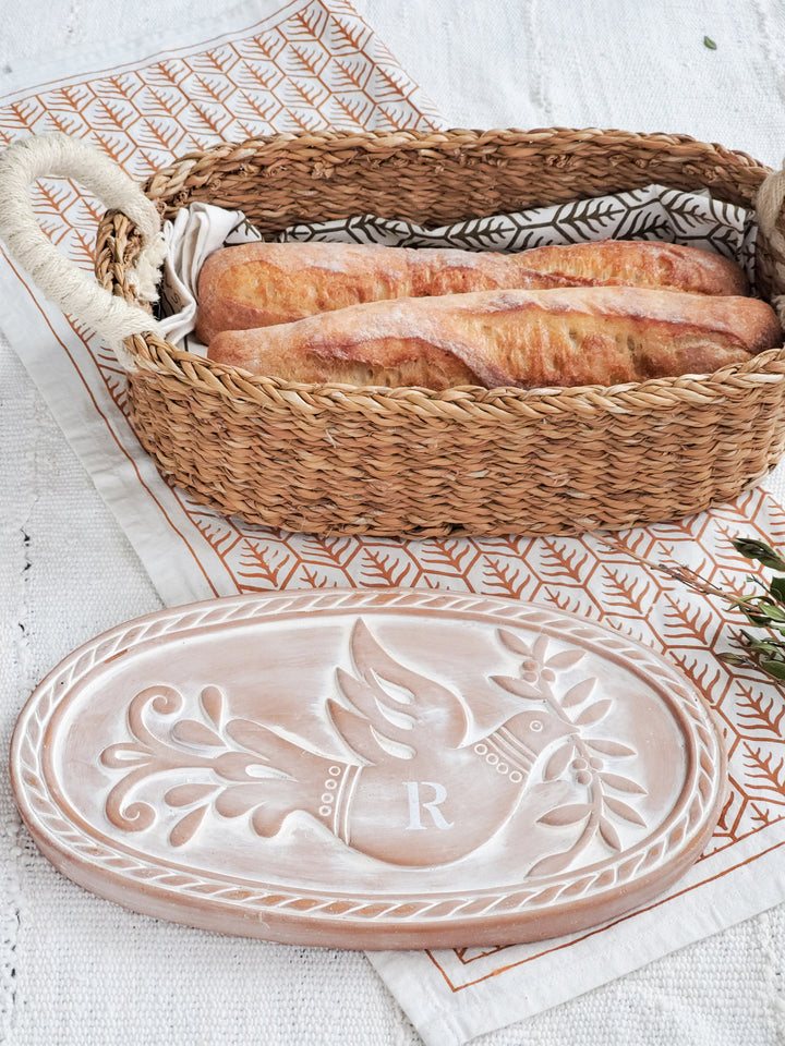 Hand engraved terracotta plate with a bird & leaf design with an oval basket and hand screen-printed tea towels in two colors on natural cotton