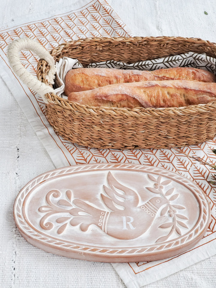 Hand engraved terracotta bread warmer with a bird & leaf design with an oval basket and hand screen-printed tea towels printed in two colors on natural cotton